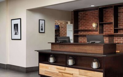 Contemporary reception desk featuring warm wood finishes, exposed brick accents, and modern décor at Wyndham Garden Pittsburgh Airport.