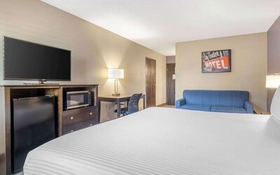 Guest room featuring a bed, blue sofa, television, mini fridge, microwave, and workspace. Best Western McCarran Inn.
