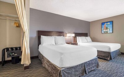 Guest room featuring two beds, bedside lighting, an in-room safe, and open wardrobe area. Best Western McCarran Inn.