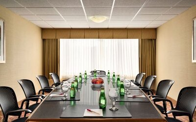 Boardroom featuring a long conference table, office chairs, bottled water, glasses, and writing pads. Crowne Plaza Englewood.