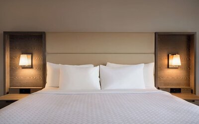 King guest room featuring a large bed with padded headboard, bedside tables, and integrated reading lights. Crowne Plaza Englewood.