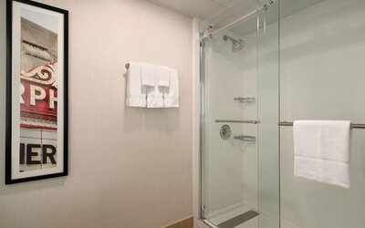 Guest bathroom featuring a glass-enclosed shower, wall-mounted showerhead, fresh towels, and contemporary décor. Crowne Plaza Englewood.