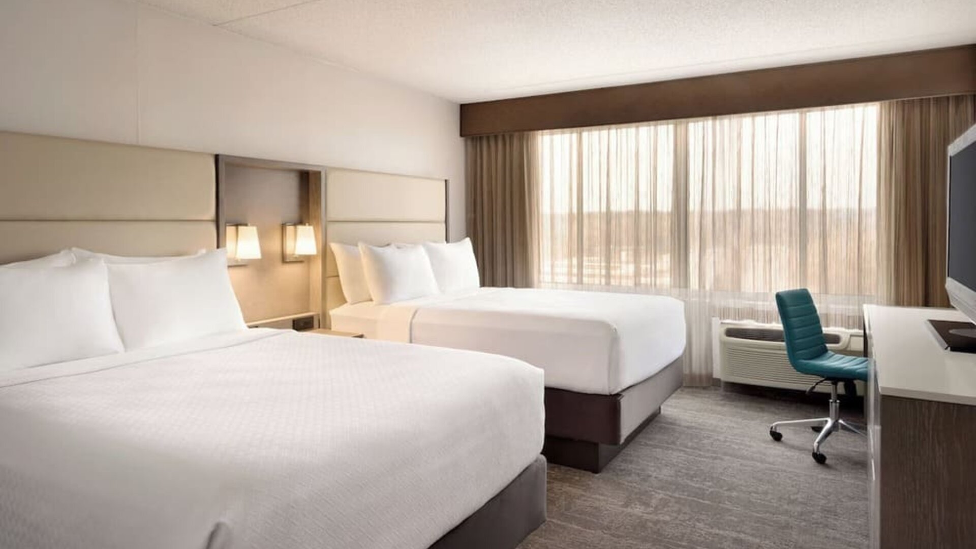 Guest room featuring two beds, large window, workspace, television, and contemporary furnishings. Crowne Plaza Englewood.
