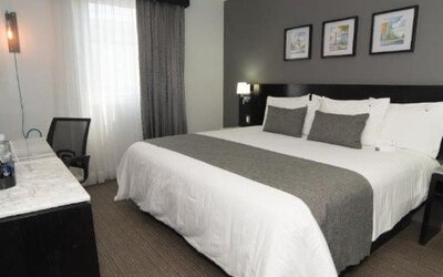 Guest room featuring a king bed, work desk, bedside lighting and modern neutral décor. LaiLa Hotel CDMX.