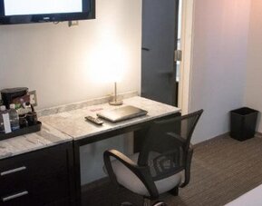In-room workspace featuring a marble-top desk, ergonomic chair, coffee station and flat-screen TV. LaiLa Hotel CDMX.