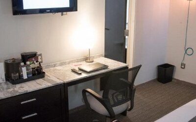In-room workspace featuring a marble-top desk, ergonomic chair, coffee station and flat-screen TV. LaiLa Hotel CDMX.
