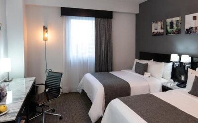 Guest room featuring two beds, a work desk, flat-screen TV and contemporary décor. LaiLa Hotel CDMX.