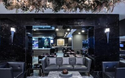Contemporary hotel dining area with tables, chairs and large street-facing windows. LaiLa Hotel CDMX.