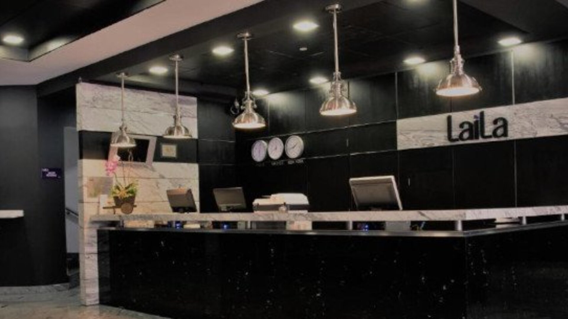 Modern reception desk featuring black and marble finishes with pendant lighting. LaiLa Hotel CDMX.