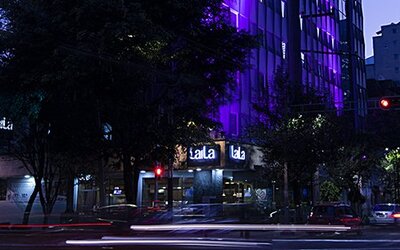 Evening exterior view of LaiLa Hotel CDMX with illuminated signage and purple accent lighting.