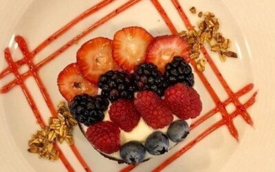 Elegant dessert topped with fresh strawberries, raspberries, blackberries and blueberries with decorative fruit sauce. LaiLa Hotel CDMX.