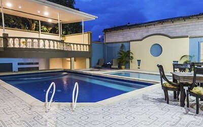 Outdoor swimming pool with patio dining area and covered terrace at Hotel Puerta de Oro.