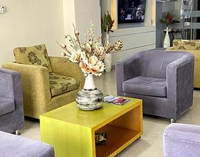 Lobby seating area with green and grey armchairs, coffee table and floral arrangement at Hotel Puerta de Oro.
