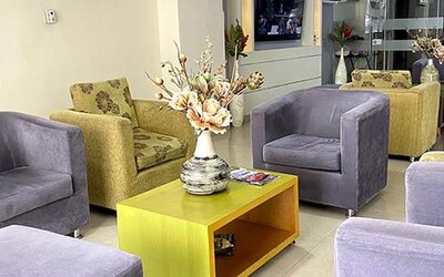 Lobby seating area with green and grey armchairs, coffee table and floral arrangement at Hotel Puerta de Oro.