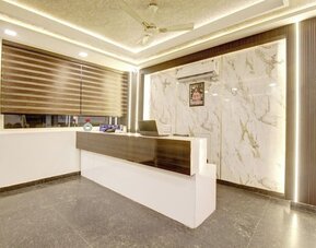 Modern hotel reception desk with dark wood and white finishes, marble-patterned feature wall, vertical accent lighting, large window with striped blinds, ceiling fan and polished gray flooring.