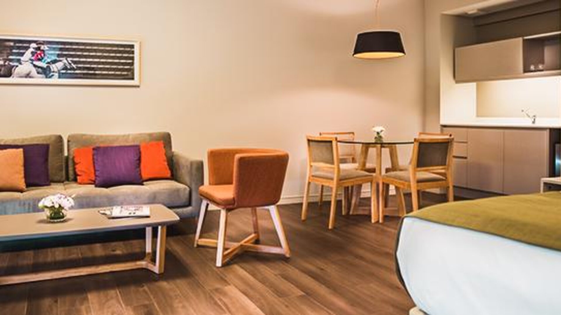 Guest room with a sofa, dining table, kitchenette, and bed in an open-plan layout at Dazzler by Wyndham Polo.