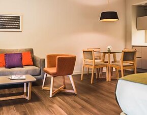 Guest room with a sofa, dining table, kitchenette, and bed in an open-plan layout at Dazzler by Wyndham Polo.