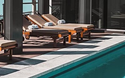 Outdoor pool deck with wooden loungers and folded towels beside a swimming pool at Dazzler by Wyndham Polo.