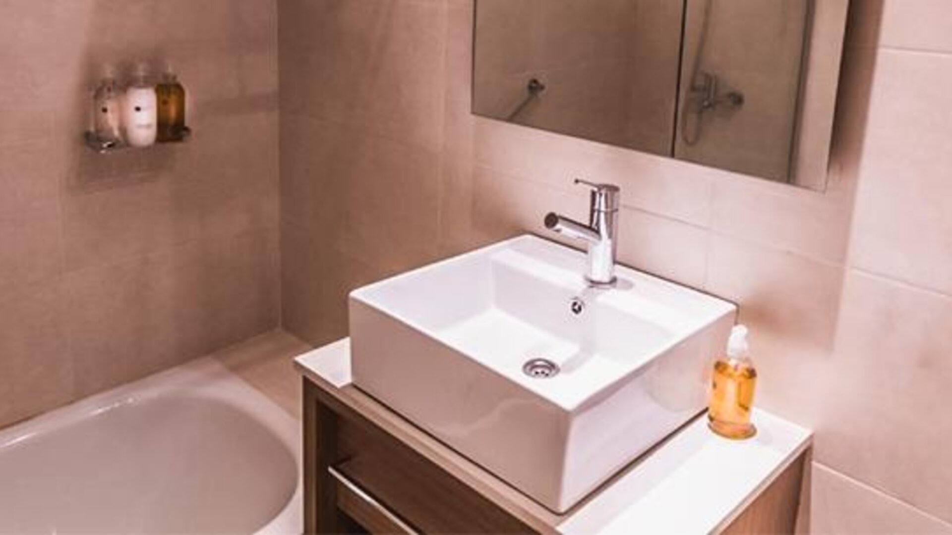 Modern bathroom with a white vessel sink, bathtub, wall mirror, and toiletries at Dazzler by Wyndham Polo.