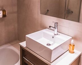 Modern bathroom with a white vessel sink, bathtub, wall mirror, and toiletries at Dazzler by Wyndham Polo.