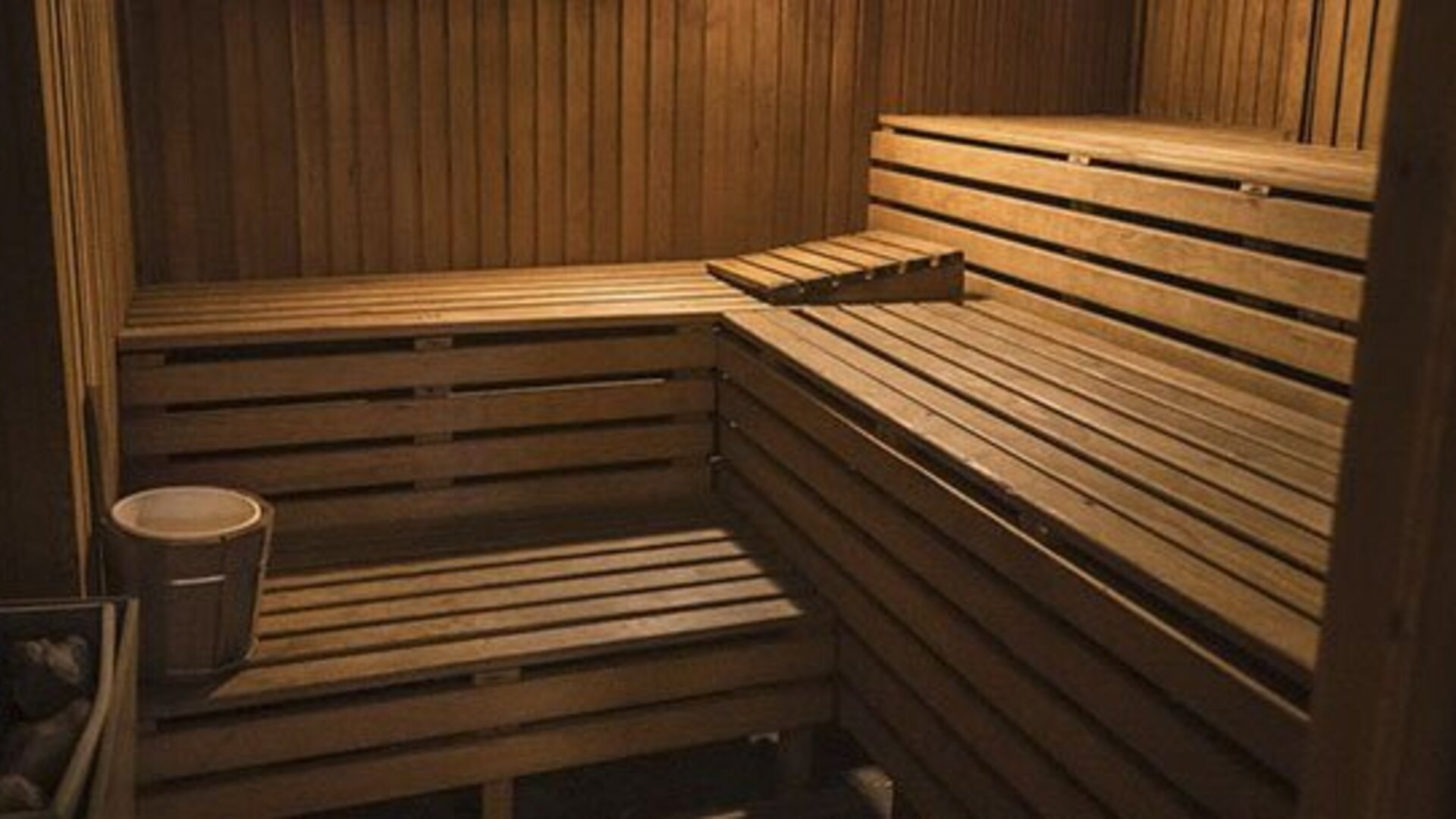 Wood-paneled sauna with tiered benches, a heater, and bucket inside at El Conquistador Hotel.