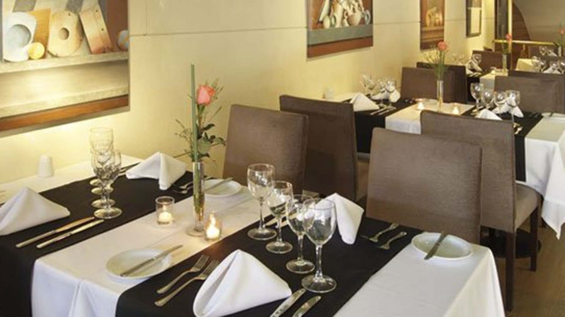 Dining room with white tablecloths, place settings, wine glasses, and floral centerpieces at El Conquistador Hotel.