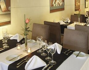 Dining room with white tablecloths, place settings, wine glasses, and floral centerpieces at El Conquistador Hotel.