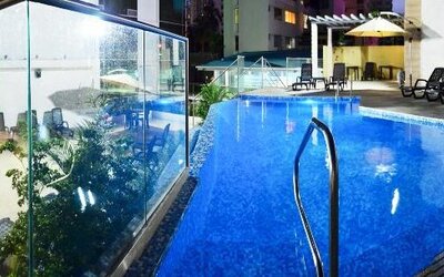 Outdoor swimming pool with blue water, glass panels, lounge chairs, and umbrellas at Hotel Grand International.