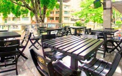 Outdoor terrace with black tables and chairs overlooking trees and surrounding buildings at Hotel Grand International.