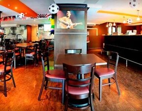 Restaurant and bar with wooden tables, chairs, a long counter, and soccer-themed hanging decorations at Hotel Grand International.