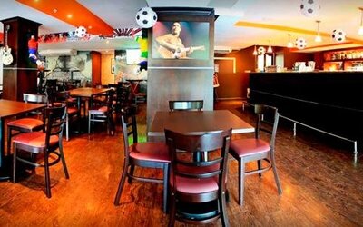 Restaurant and bar with wooden tables, chairs, a long counter, and soccer-themed hanging decorations at Hotel Grand International.