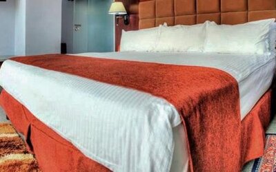 Spacious guest room with a king bed, seating area, desk, television, and large windows at Hotel Grand International.
