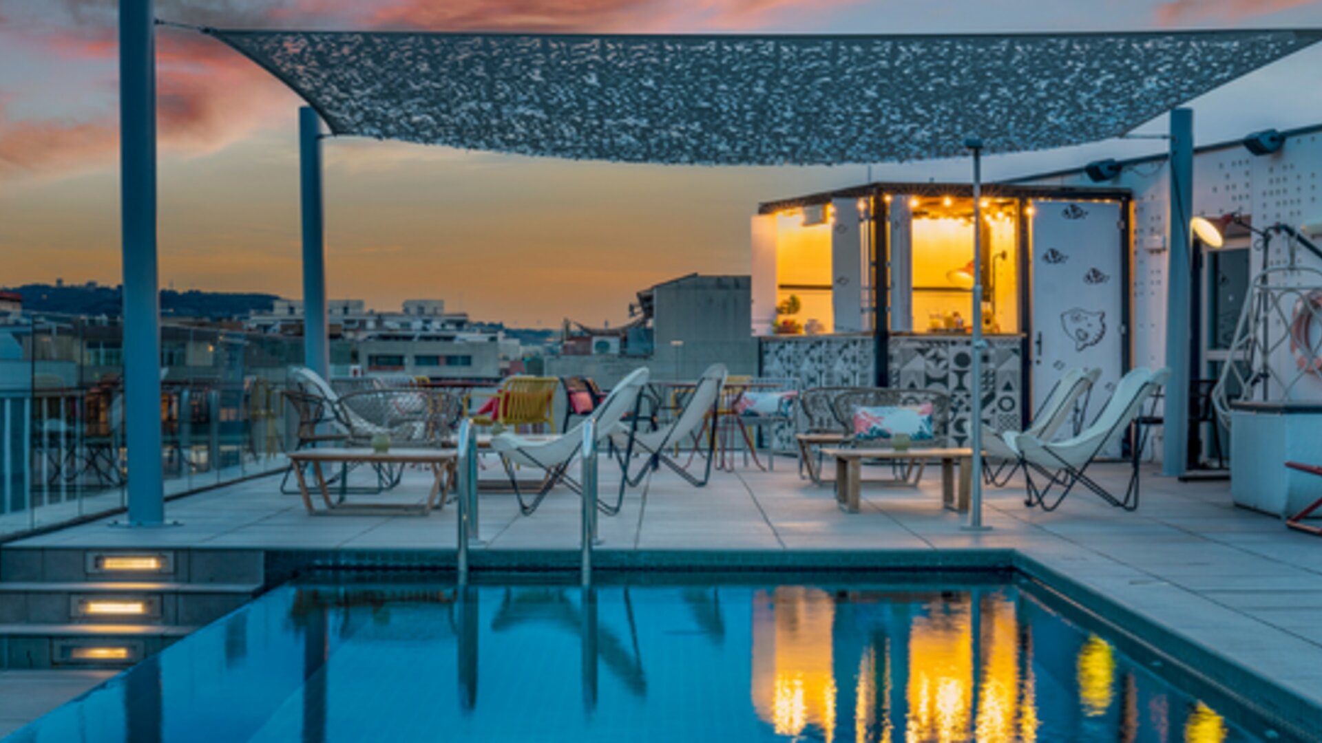 Rooftop pool with lounge chairs, outdoor seating, and a poolside bar area under a canopy at Hotel ibis Styles Barcelona City Bogatell.