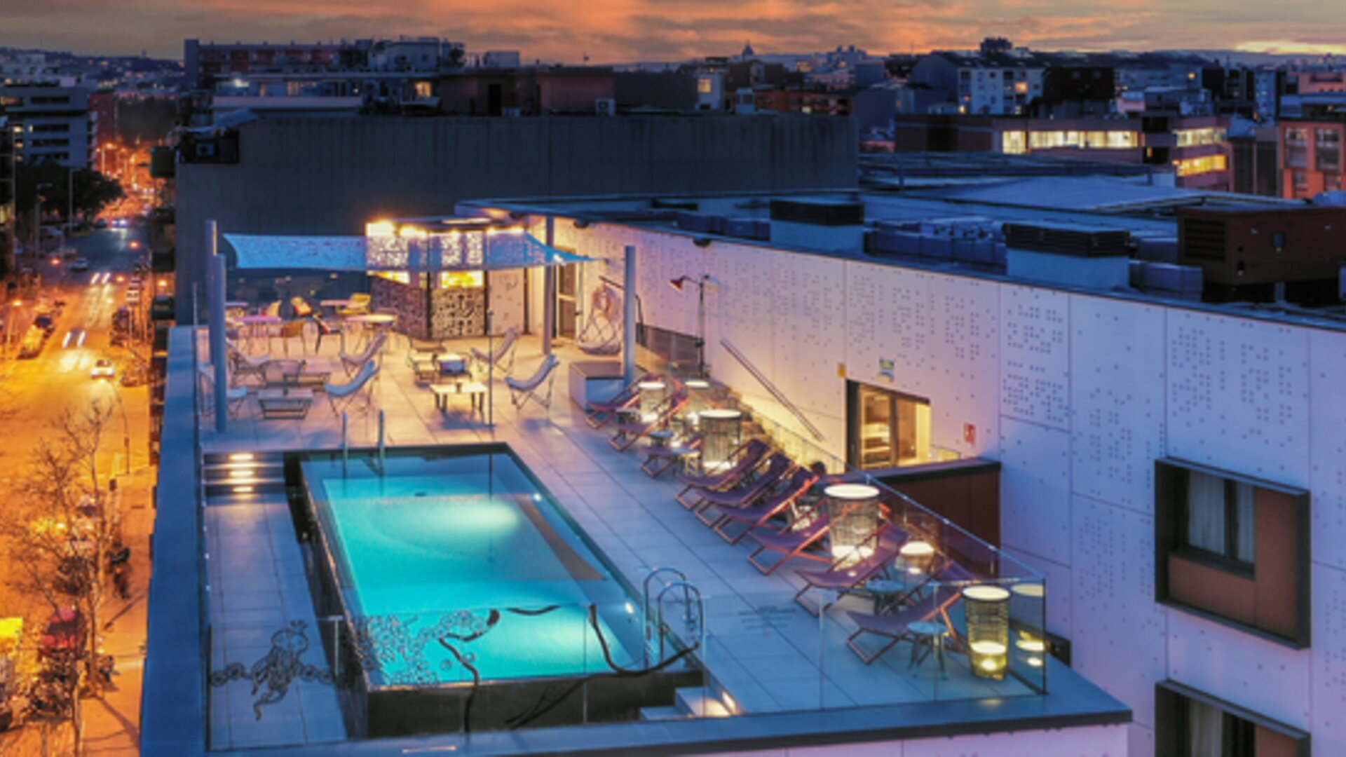Rooftop swimming pool surrounded by lounge chairs, cabanas, and outdoor seating at Hotel ibis Styles Barcelona City Bogatell.