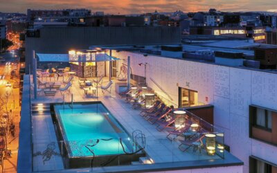 Rooftop swimming pool surrounded by lounge chairs, cabanas, and outdoor seating at Hotel ibis Styles Barcelona City Bogatell.