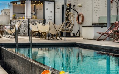 Rooftop terrace overlooking the city with a swimming pool, lounge chairs, canopy, and outdoor bar at Hotel ibis Styles Barcelona City Bogatell.