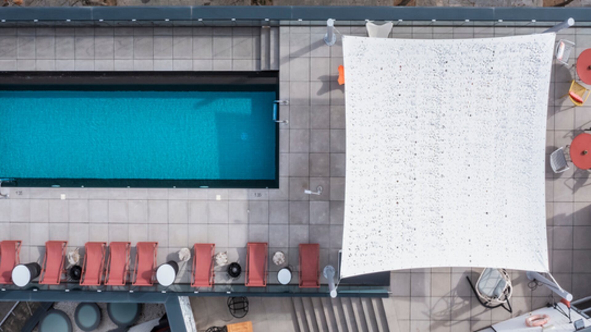 Aerial view of the rooftop pool, surrounding lounge chairs, canopy, and terrace seating at Hotel ibis Styles Barcelona City Bogatell.