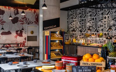 Breakfast buffet with pastries, fruit, cold foods, and drinks beside a patterned dining area at Hotel ibis Styles Barcelona City Bogatell.