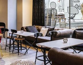 Indoor lounge with sofas, armchairs, round tables, pendant lighting, and views of the rooftop terrace at Hotel ibis Styles Barcelona City Bogatell.
