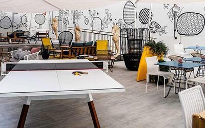 Leisure area with a table tennis table, colorful chairs, tables, and illustrated wall murals at Hotel ibis Styles Barcelona City Bogatell.