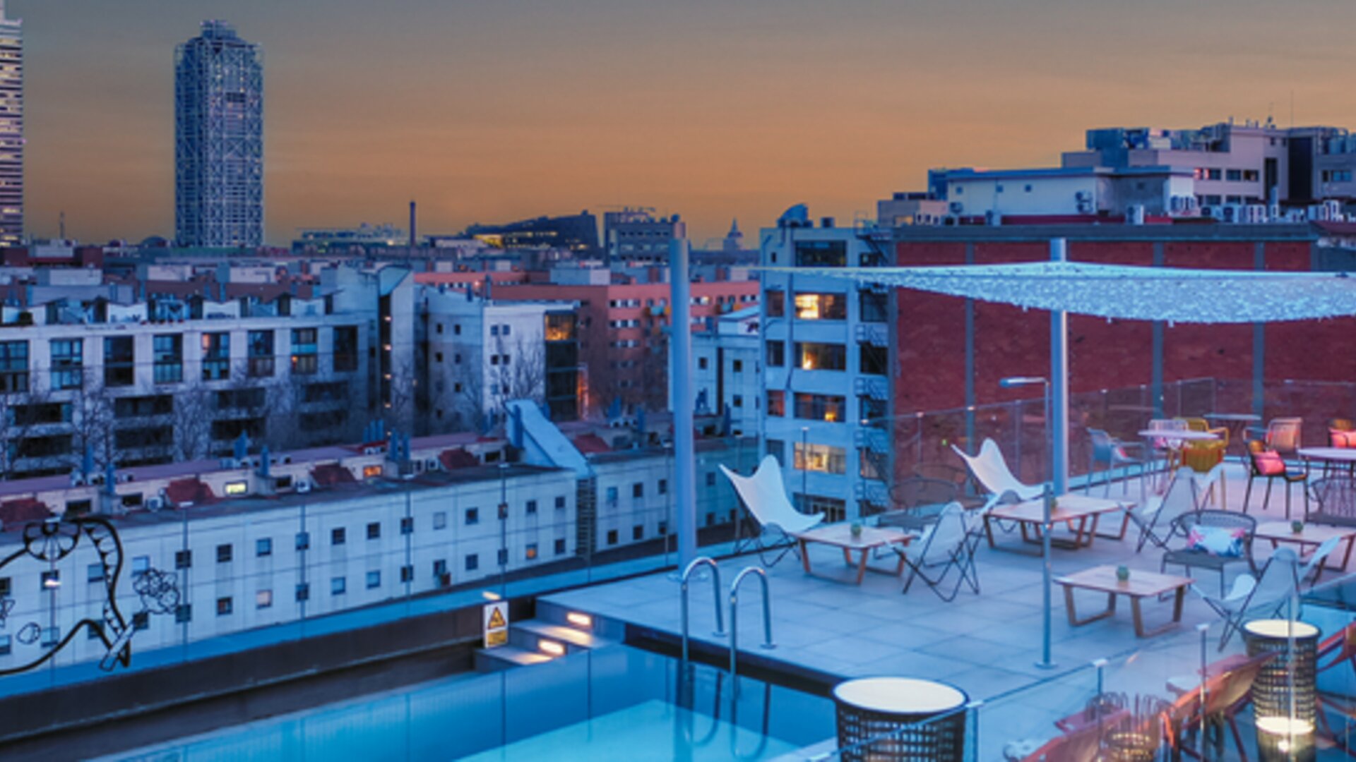 Rooftop terrace with swimming pool, lounge chairs, city skyline, and outdoor seating at Hotel ibis Styles Barcelona City Bogatell.