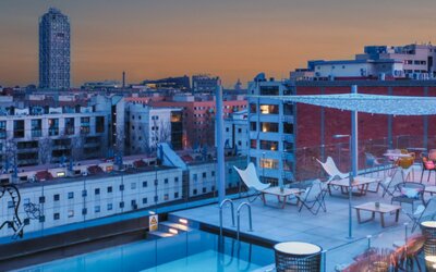 Rooftop terrace with swimming pool, lounge chairs, city skyline, and outdoor seating at Hotel ibis Styles Barcelona City Bogatell.