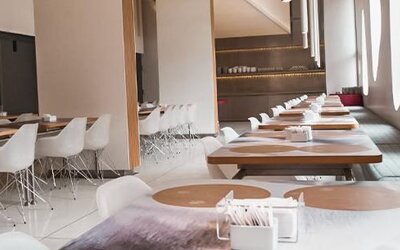 Bright restaurant dining area with wooden tables, white chairs, place settings, and large oval windows at Dazzler by Wyndham Buenos Aires Recoleta.