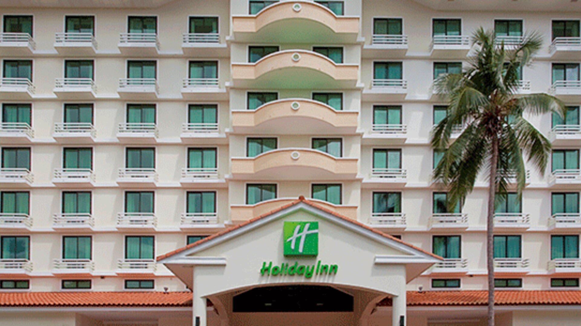 Exterior view of the multi-story Holiday Inn hotel building with balconies and a palm tree at Holiday Inn Panama Canal.