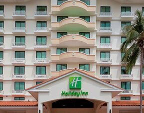 Exterior view of the multi-story Holiday Inn hotel building with balconies and a palm tree at Holiday Inn Panama Canal.