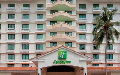 Exterior view of the multi-story Holiday Inn hotel building with balconies and a palm tree at Holiday Inn Panama Canal.