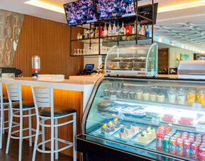 Hotel café and snack shop with a counter, refrigerated display case, high-top seating and refreshments at Holiday Inn Panama Canal.