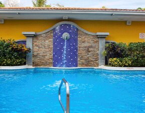 Outdoor swimming pool with blue water, tropical landscaping and a decorative tiled waterfall feature at Holiday Inn Panama Canal.