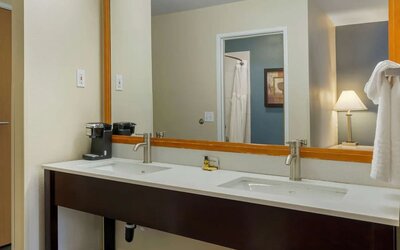 Double-sink vanity with a large mirror, coffee maker, and towels at Best Western Plus Mountain View Auburn Inn.