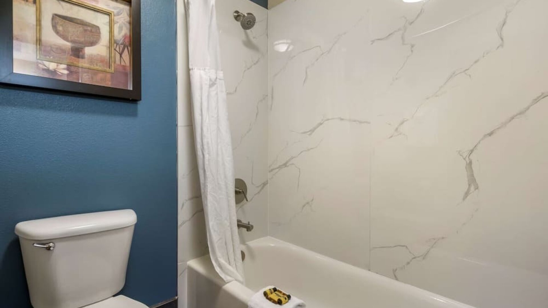 Bathroom with a bathtub, shower, toilet, and marble-look wall surround at Best Western Plus Mountain View Auburn Inn.